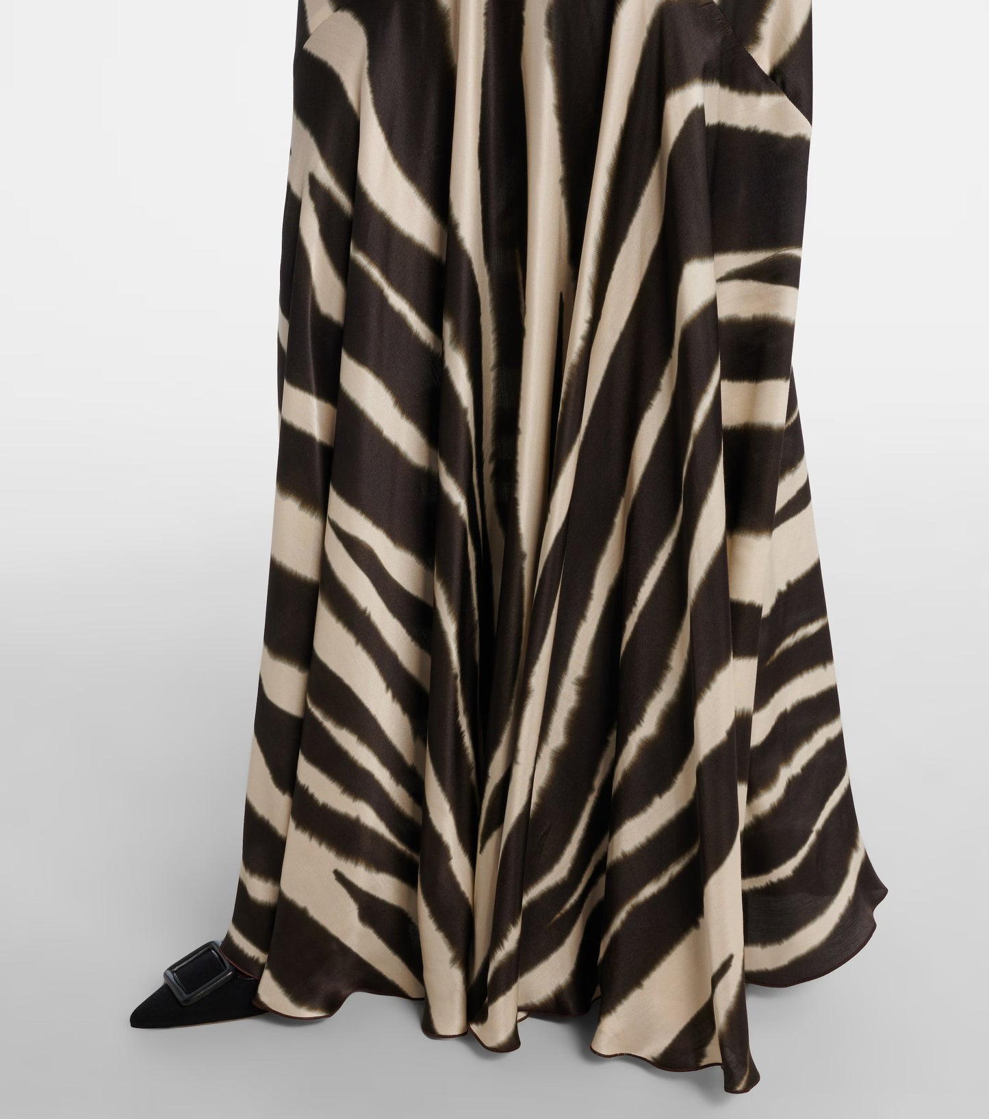 A woman modelling a floor-length, satin-look maxi dress featuring a bold, blurred zebra print and contrasting black textured shoulder ties.