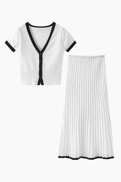 White - Woman wearing a white ribbed knit two-piece set featuring a short-sleeve V-neck crop top and a pleated midi skirt, both finished with black contrast trim.