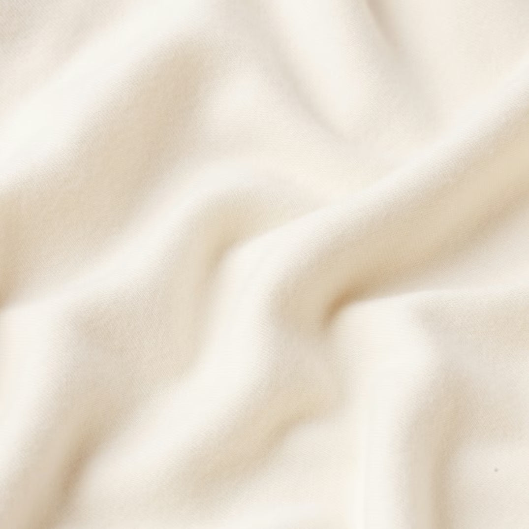 Ivory - A woman wearing a fitted white mini dress featuring a deep V-neckline, satin bow ties at the shoulders and bust, and a plush faux fur trim at the hem.