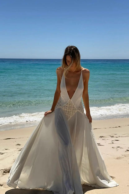 Ivory - A woman wearing an elegant, flowing off-white maxi dress featuring a deep plunging V-neckline and a textured appliqué waist panel, standing against a neutral background.