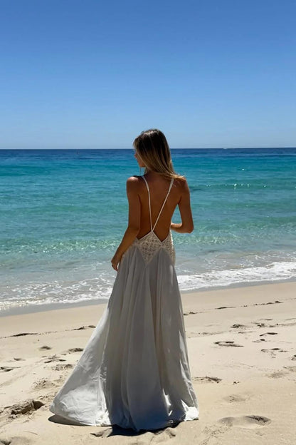 Ivory - A woman wearing an elegant, flowing off-white maxi dress featuring a deep plunging V-neckline and a textured appliqué waist panel, standing against a neutral background.