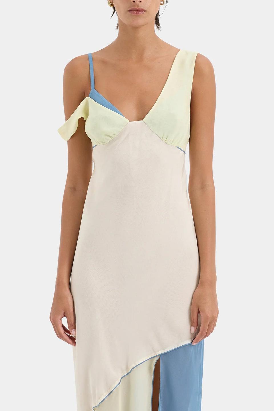 Ecru Multi - A woman wearing a long, fluid colourblock maxi dress in pale yellow, cream, and light blue, featuring an asymmetrical neckline, a high side slit, and semi-sheer skirt panels.