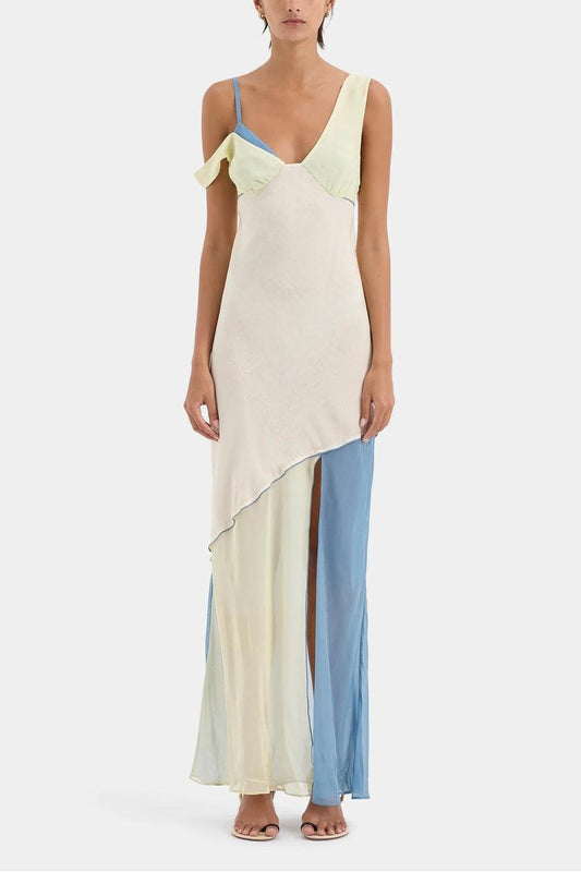 Ecru Multi - A woman wearing a long, fluid colourblock maxi dress in pale yellow, cream, and light blue, featuring an asymmetrical neckline, a high side slit, and semi-sheer skirt panels.
