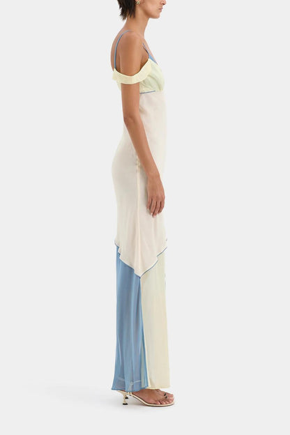 Ecru Multi - A woman wearing a long, fluid colourblock maxi dress in pale yellow, cream, and light blue, featuring an asymmetrical neckline, a high side slit, and semi-sheer skirt panels.