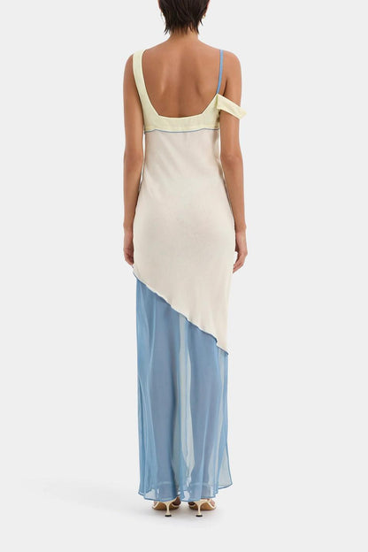Ecru Multi - A woman wearing a long, fluid colourblock maxi dress in pale yellow, cream, and light blue, featuring an asymmetrical neckline, a high side slit, and semi-sheer skirt panels.