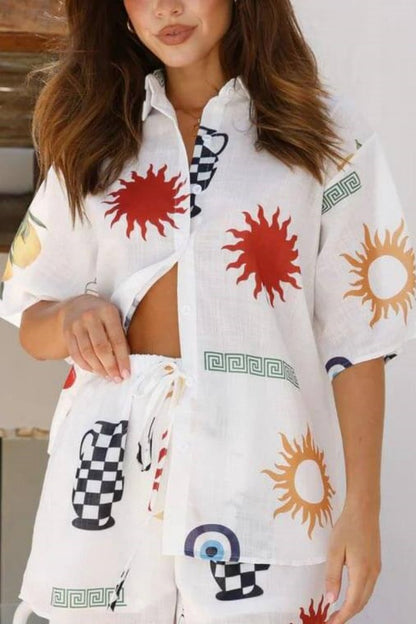 White - Women's white short-sleeved button-down shirt featuring a colourful Mediterranean motif print including suns, checkered vases, and evil eyes, worn partially unbuttoned over matching drawstring shorts.