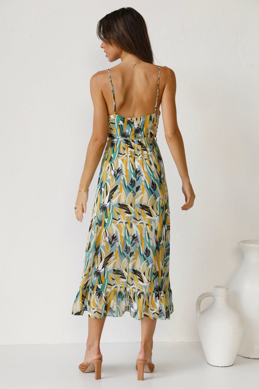 Red - A woman modelling a flowing midi dress featuring a vibrant abstract brushstroke print in yellow, green, and blue, complete with delicate straps and a ruffled hemline.