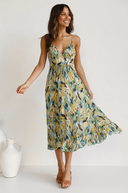 Yellow - A woman modelling a flowing midi dress featuring a vibrant abstract brushstroke print in yellow, green, and blue, complete with delicate straps and a ruffled hemline.