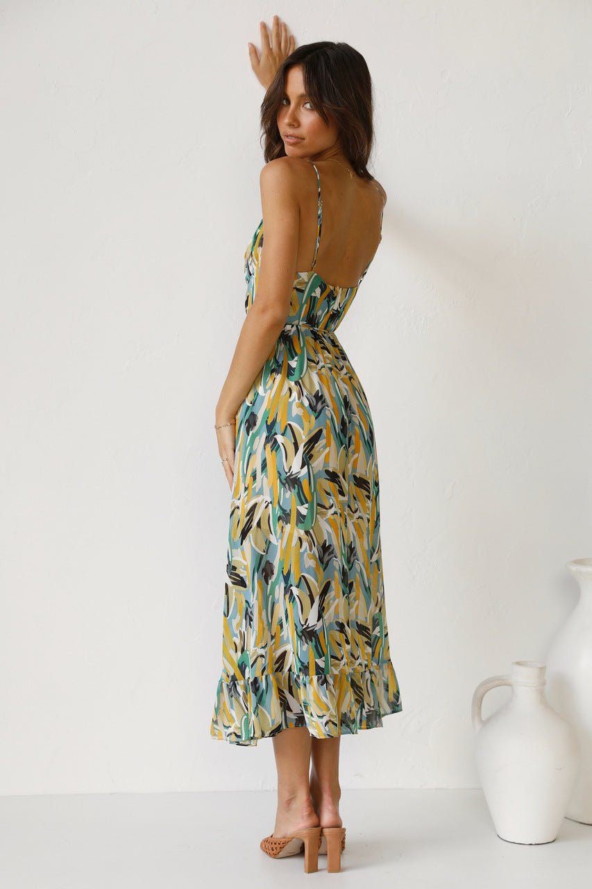 Red - A woman modelling a flowing midi dress featuring a vibrant abstract brushstroke print in yellow, green, and blue, complete with delicate straps and a ruffled hemline.