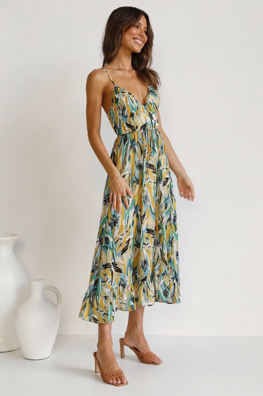 Red - A woman modelling a flowing midi dress featuring a vibrant abstract brushstroke print in yellow, green, and blue, complete with delicate straps and a ruffled hemline.