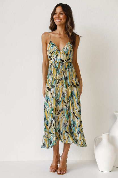 Red - A woman modelling a flowing midi dress featuring a vibrant abstract brushstroke print in yellow, green, and blue, complete with delicate straps and a ruffled hemline.