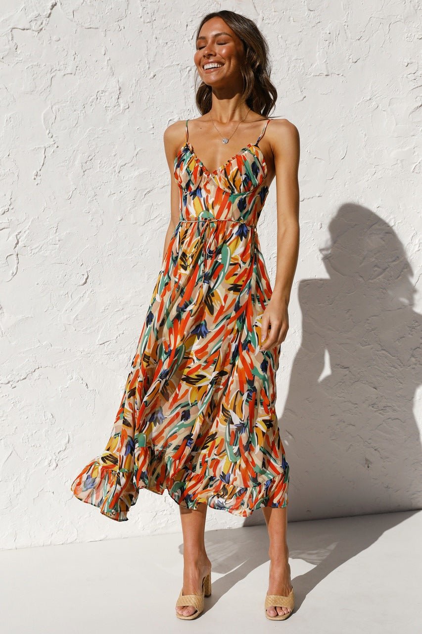 Red - A woman modelling a flowing midi dress featuring a vibrant abstract brushstroke print in yellow, green, and blue, complete with delicate straps and a ruffled hemline.