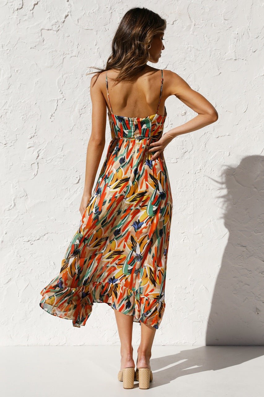Red - A woman modelling a flowing midi dress featuring a vibrant abstract brushstroke print in yellow, green, and blue, complete with delicate straps and a ruffled hemline.