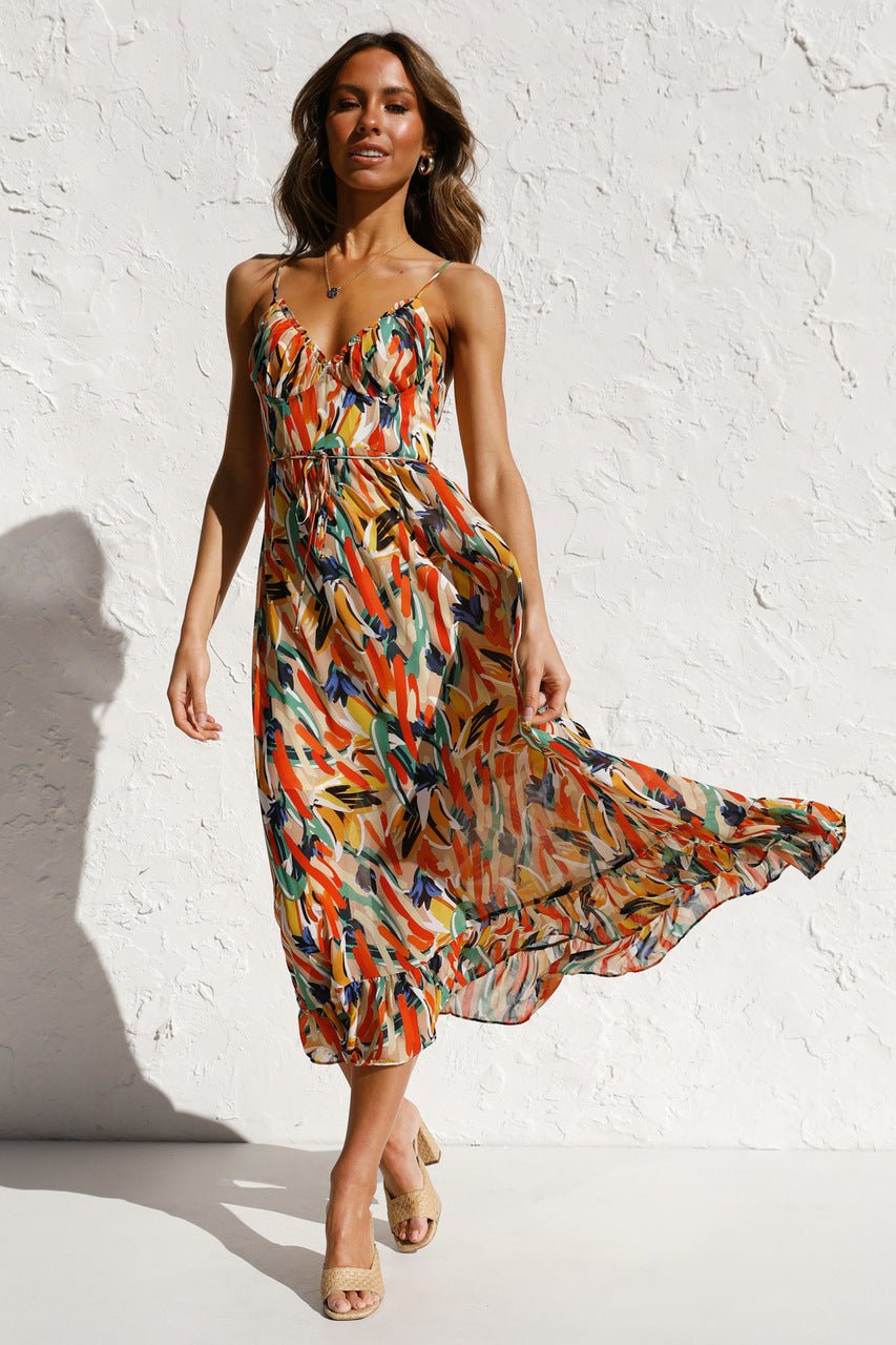 Red - A woman modelling a flowing midi dress featuring a vibrant abstract brushstroke print in yellow, green, and blue, complete with delicate straps and a ruffled hemline.