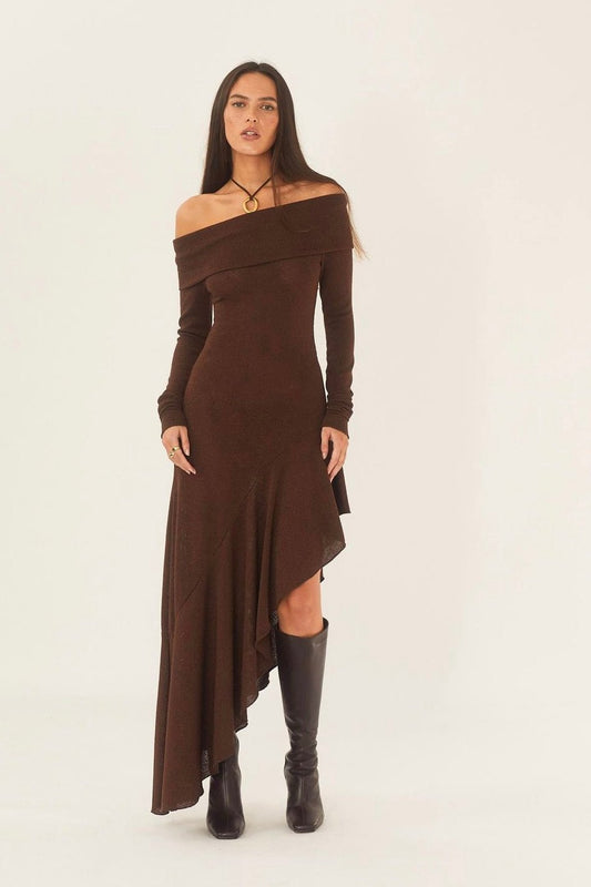 Brown - Full-length studio shot of a woman wearing a long-sleeve, off-the-shoulder brown knit dress with a dramatic asymmetrical high-low hem, paired with black stiletto boots.