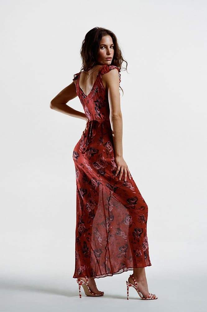 Red - A woman wearing a long, deep red maxi dress with a large pink rose floral print, featuring a scoop neckline and flutter cap sleeves.