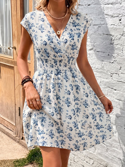 Blue - Woman modelling a lightweight animal-print v-neck mini dress with cap sleeves and a shirred waist, holding a woven bag against a white brick wall.