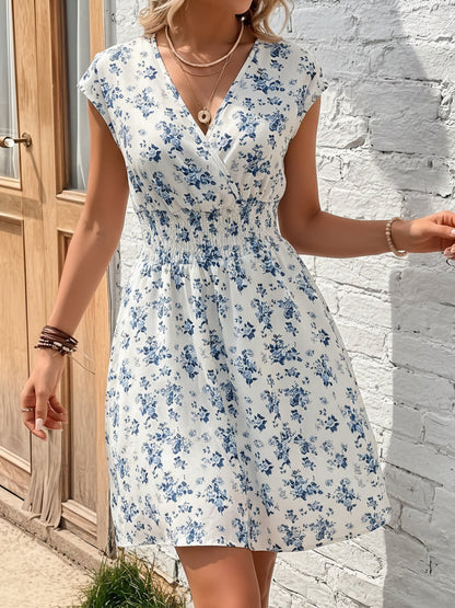 Blue - Woman modelling a lightweight animal-print v-neck mini dress with cap sleeves and a shirred waist, holding a woven bag against a white brick wall.