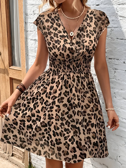 Leopard - Woman modelling a lightweight animal-print v-neck mini dress with cap sleeves and a shirred waist, holding a woven bag against a white brick wall.