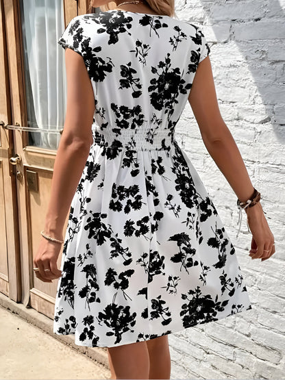 White - Woman modelling a lightweight animal-print v-neck mini dress with cap sleeves and a shirred waist, holding a woven bag against a white brick wall.