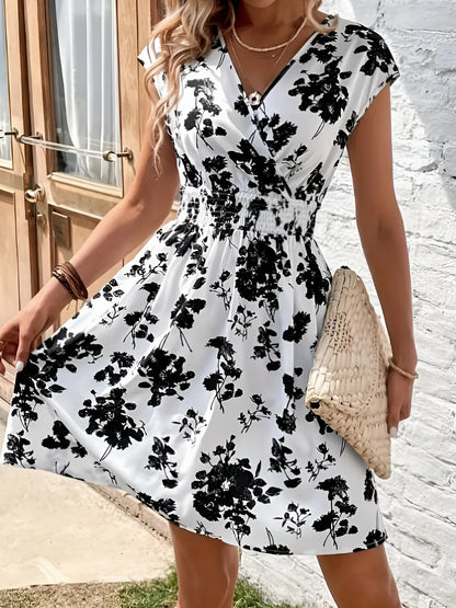 White - Woman modelling a lightweight animal-print v-neck mini dress with cap sleeves and a shirred waist, holding a woven bag against a white brick wall.