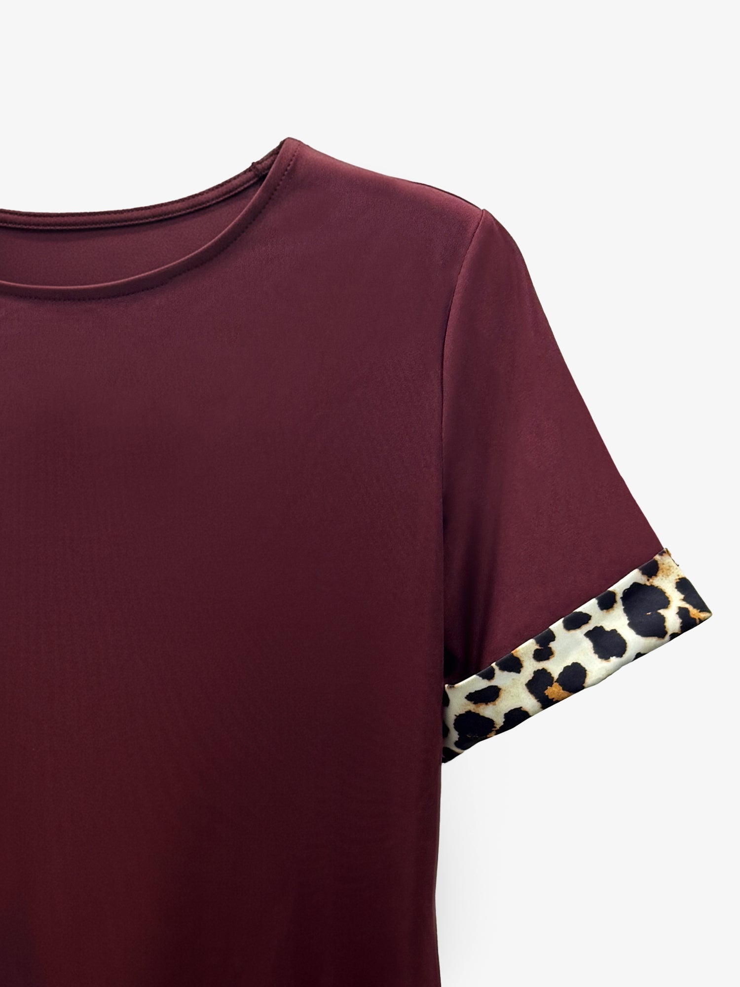 Burgundy - Woman wearing a short-sleeve shift dress featuring a high crew neckline and contrasting leopard print trim on the sleeves and hem, standing on a balcony.