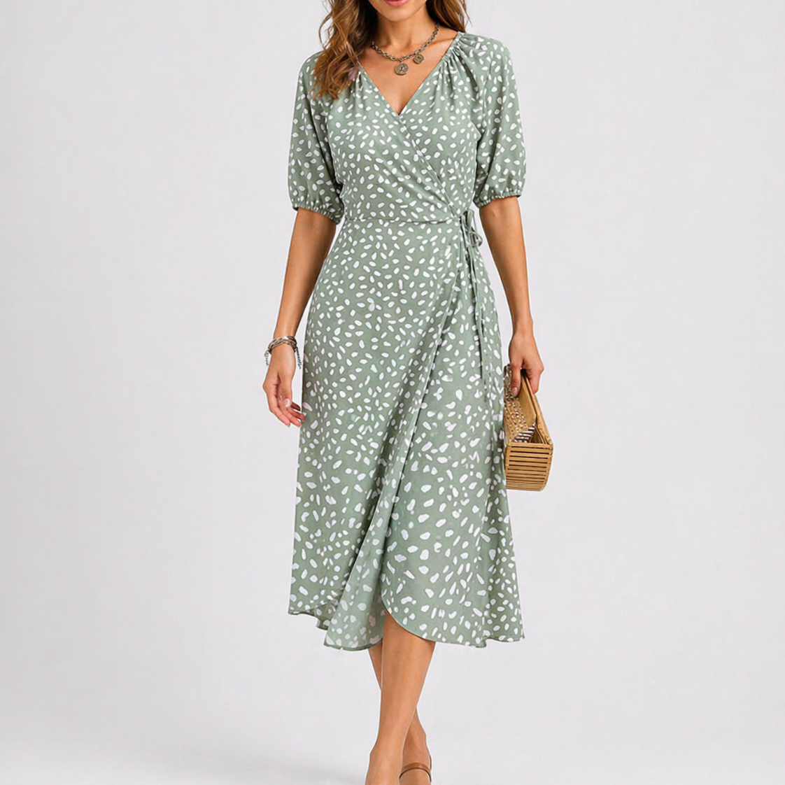 Green - Model wearing a speckled wrap midi dress with short sleeves and a side tie, styled with a woven clutch bag.