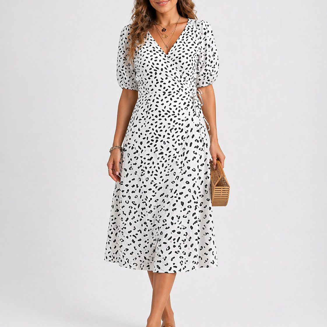 White - Model wearing a speckled wrap midi dress with short sleeves and a side tie, styled with a woven clutch bag.
