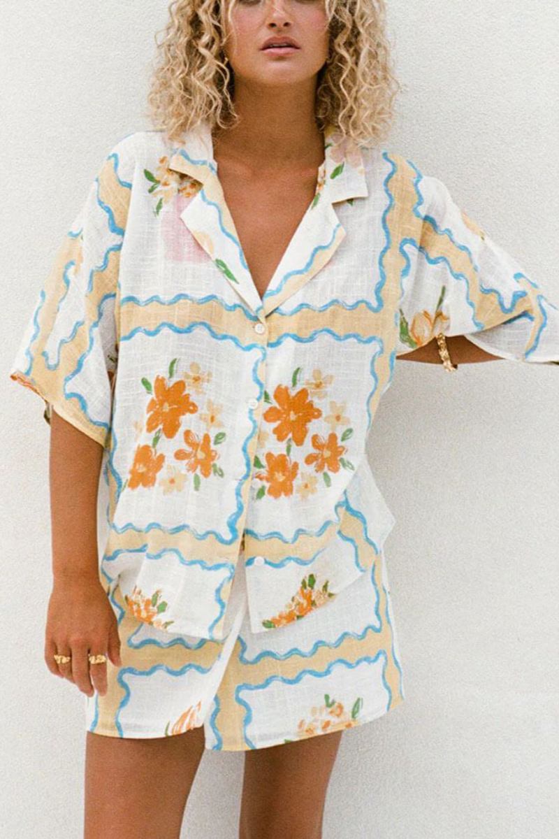 MultiColor - A woman modelling a matching white cropped short-sleeve shirt and mini wrap skirt, decorated with a yellow and blue wavy border pattern and orange floral vase illustrations.