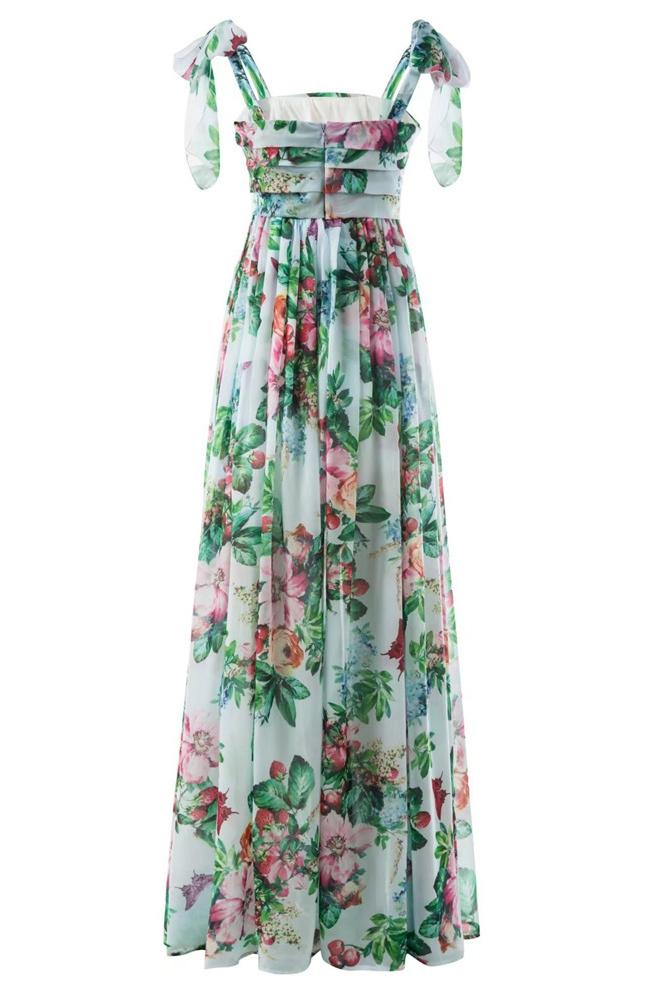 Multi - A woman models a flowing maxi dress featuring a vibrant, large-scale botanical floral print, styled with a ruched bodice and wide tie-shoulder straps, standing outdoors near a floral arrangement.