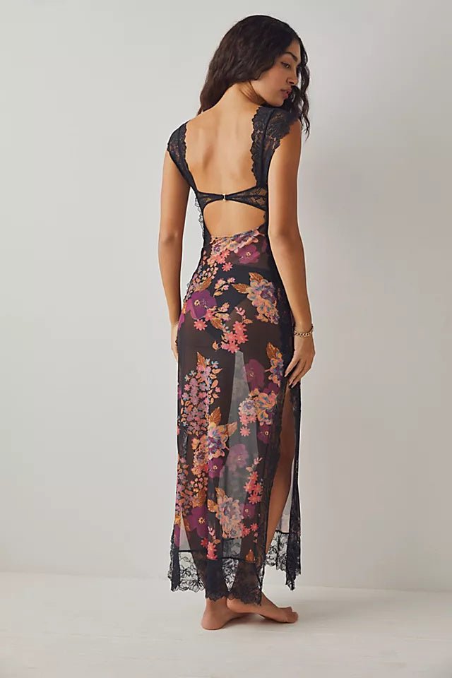 Black - A woman wearing a maxi dress featuring a black lace bodice with an under-bust cut-out and a sheer skirt with a vibrant floral print and lace trim.
