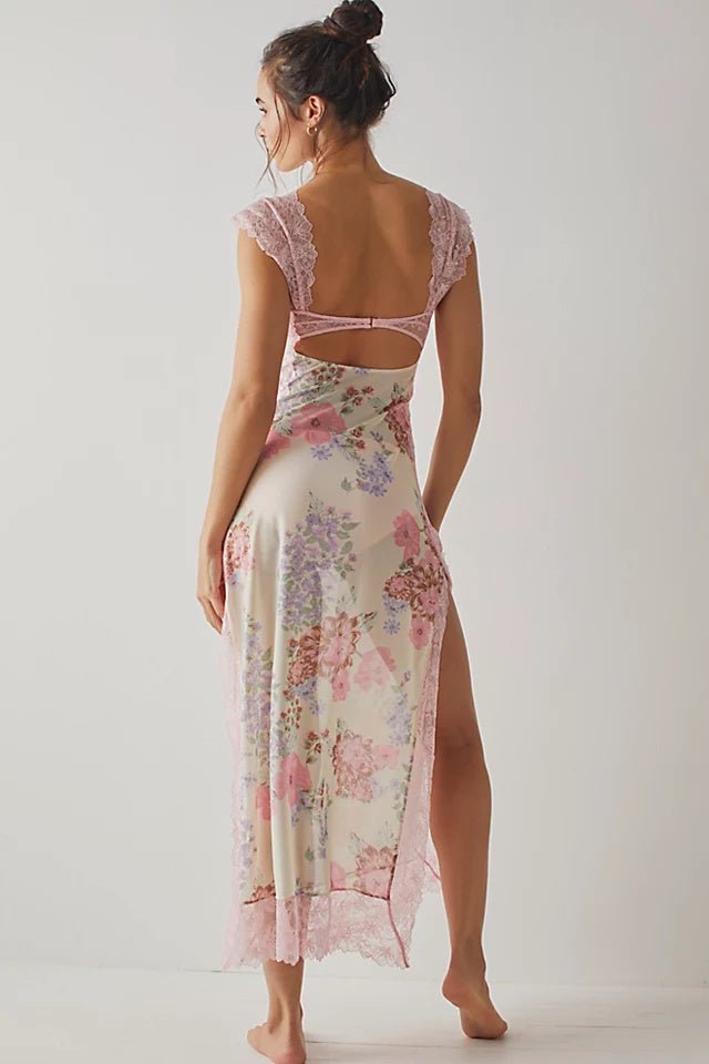 Pink - A woman wearing a maxi dress featuring a black lace bodice with an under-bust cut-out and a sheer skirt with a vibrant floral print and lace trim.