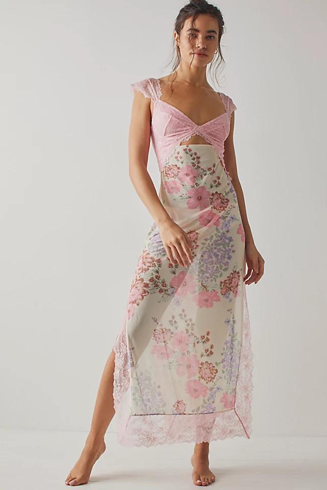 Pink - A woman wearing a maxi dress featuring a black lace bodice with an under-bust cut-out and a sheer skirt with a vibrant floral print and lace trim.