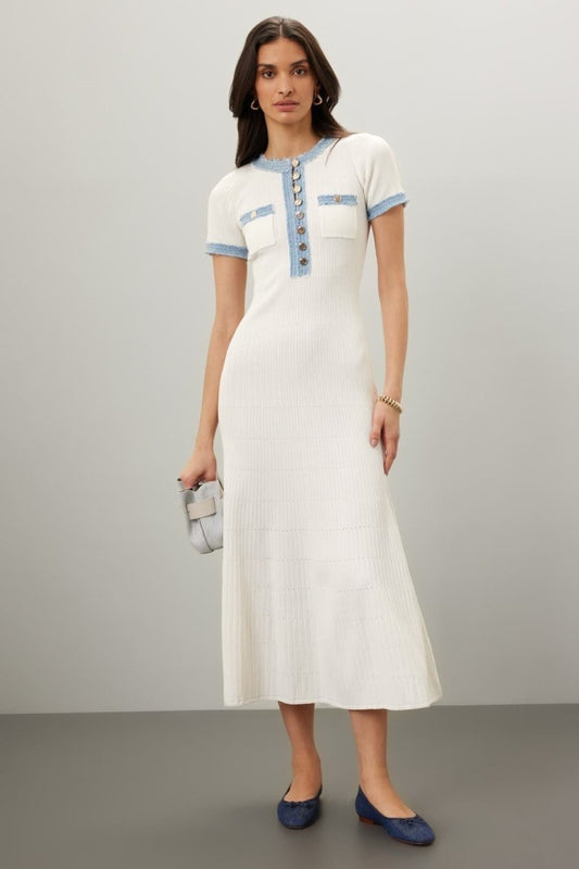 White - Full-length view of a woman wearing a white short-sleeve ribbed knit midi dress with blue frayed trim, a button placket, and chest pockets. She is styled with blue ballet flats and a grey handbag against a plain grey background.