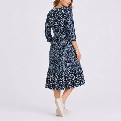 Blue - Model wearing a ditsy floral V-neck midi dress with 3/4-length sleeves and a tiered hemline.