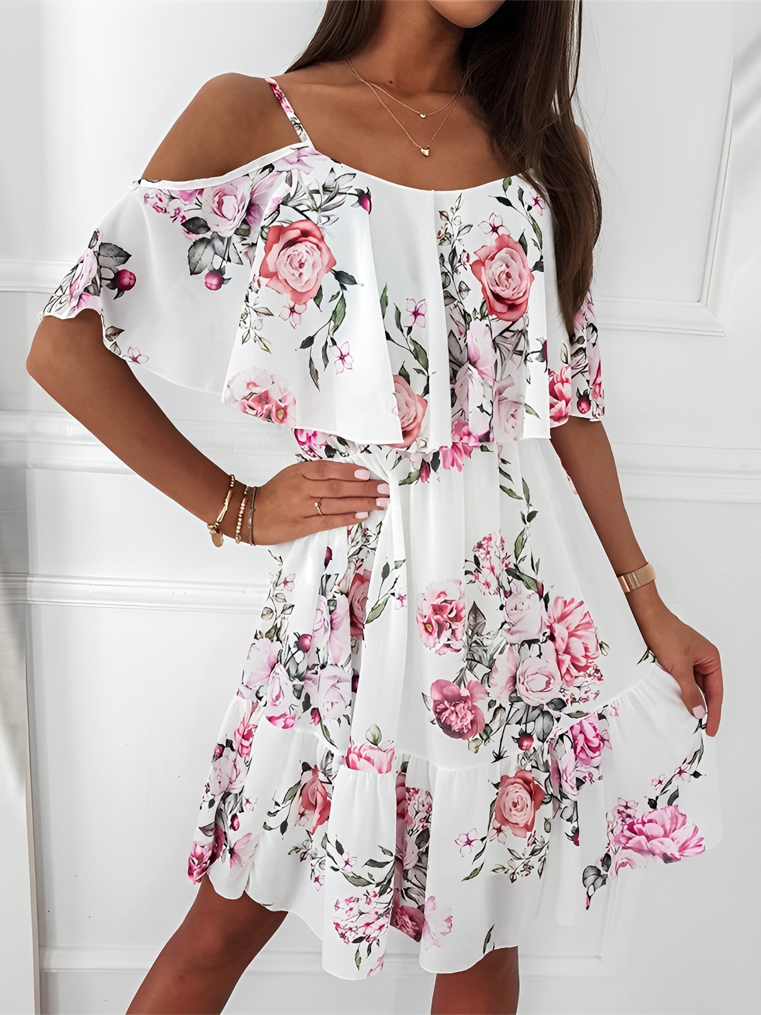 White - Woman wearing a floral print cold-shoulder tiered dress with a ruffle overlay neckline.