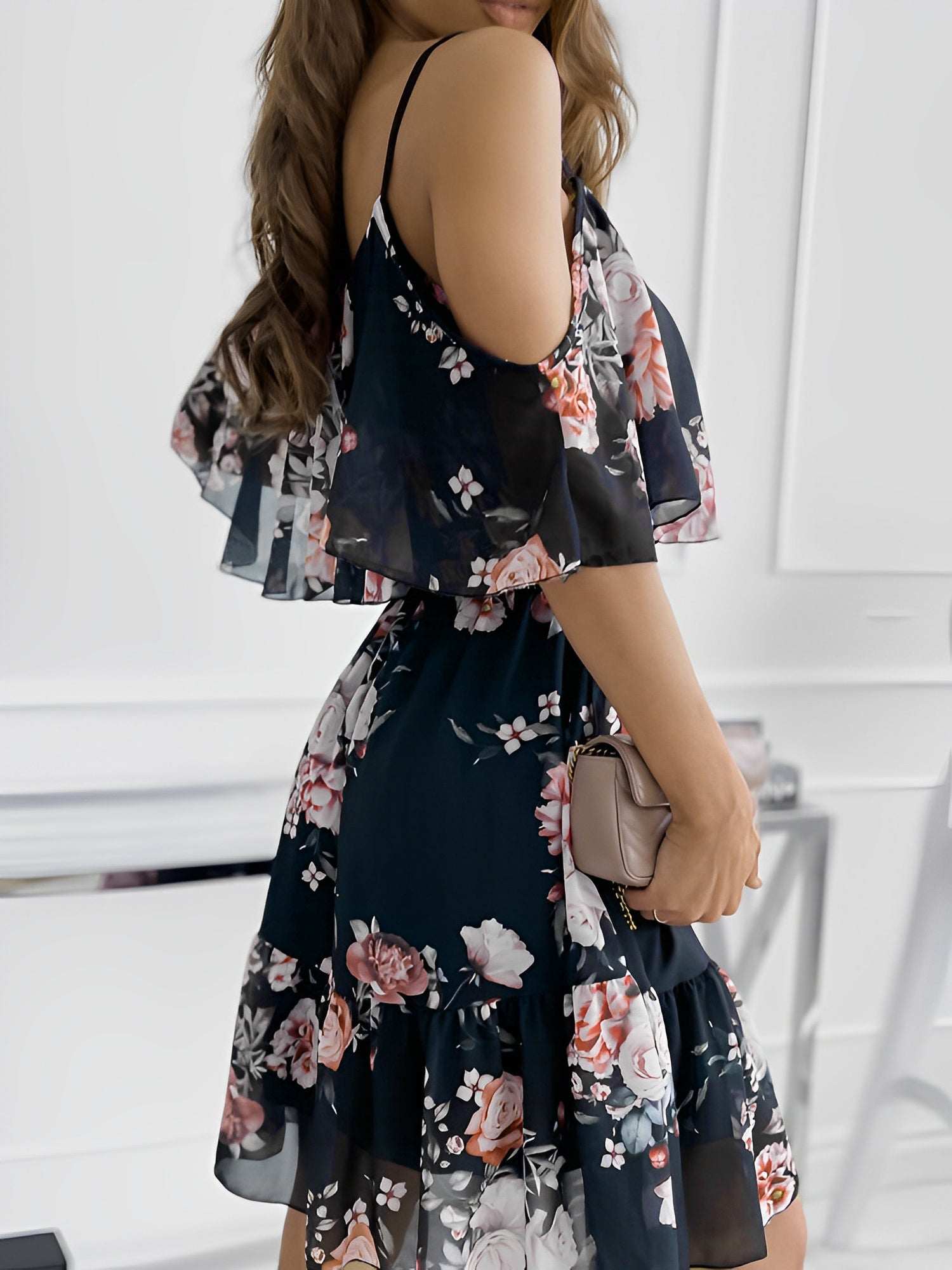 Black - Woman wearing a floral print cold-shoulder tiered dress with a ruffle overlay neckline.