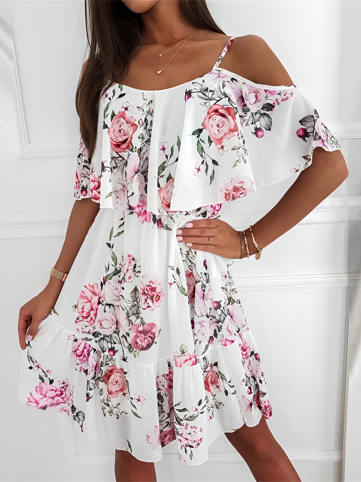 White - Woman wearing a floral print cold-shoulder tiered dress with a ruffle overlay neckline.