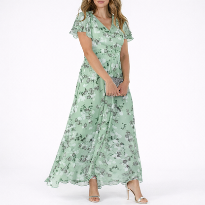 Green - Woman wearing a floral print V-neck midaxi dress with short flutter sleeves and a flowing A-line skirt, styled with a clutch and heels.