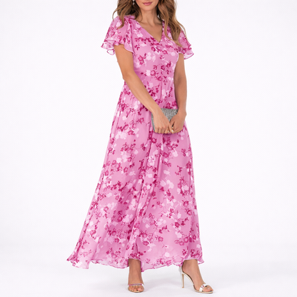 Pink - Woman wearing a floral print V-neck midaxi dress with short flutter sleeves and a flowing A-line skirt, styled with a clutch and heels.