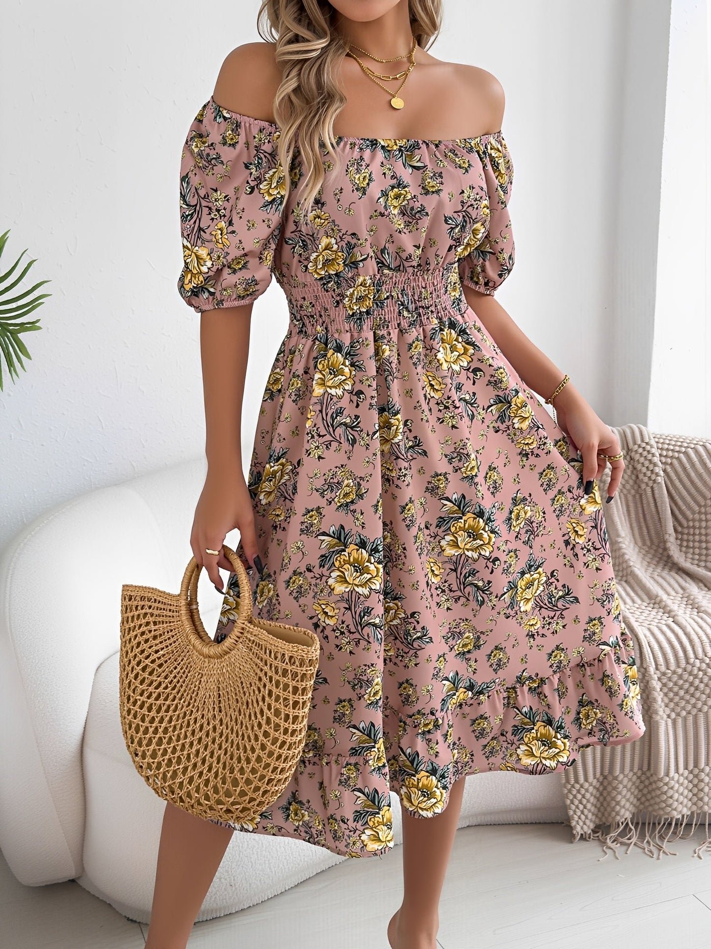 Pink - Woman wearing a floral print off-the-shoulder midi dress with a smocked waist and short puff sleeves, holding a woven straw bag