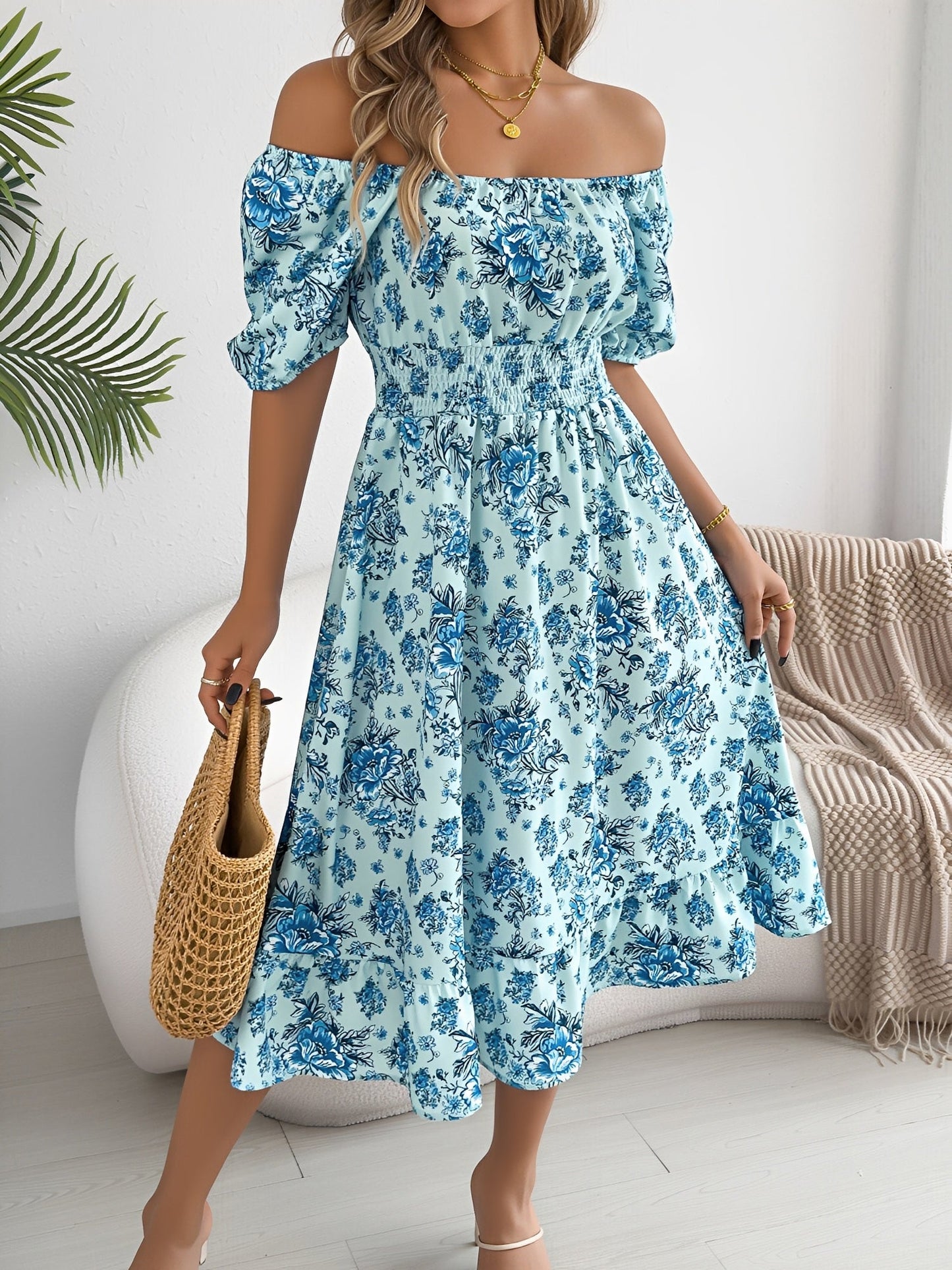 Blue - Woman wearing a floral print off-the-shoulder midi dress with a smocked waist and short puff sleeves, holding a woven straw bag