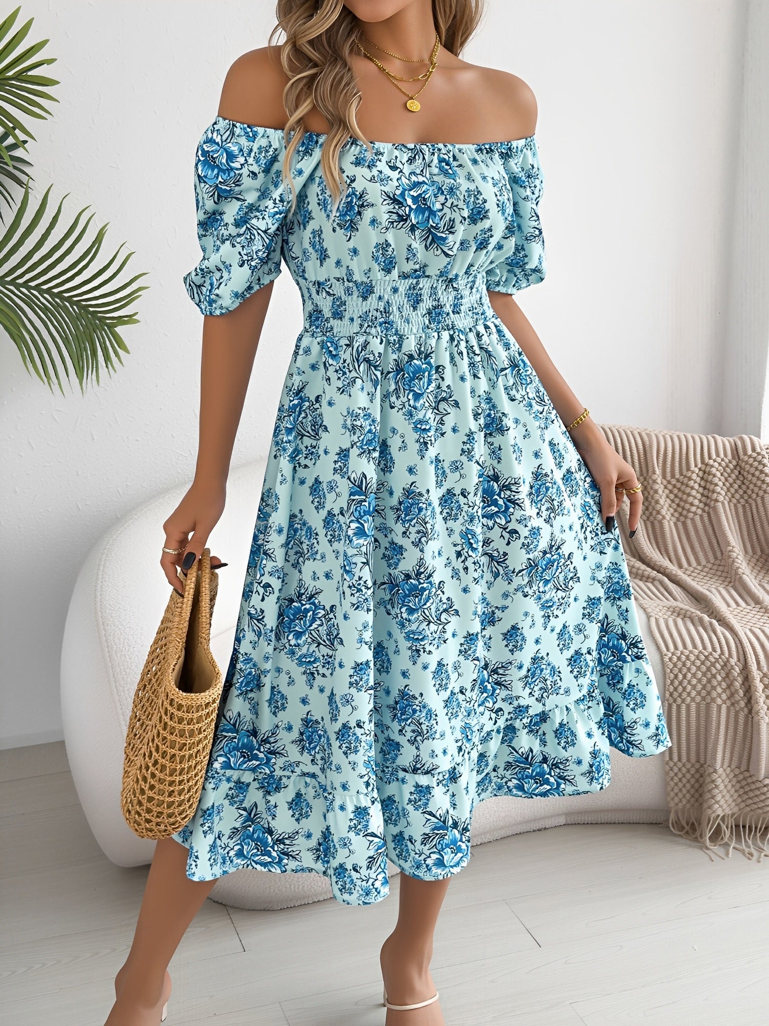 Blue - Woman wearing a floral print off-the-shoulder midi dress with a smocked waist and short puff sleeves, holding a woven straw bag