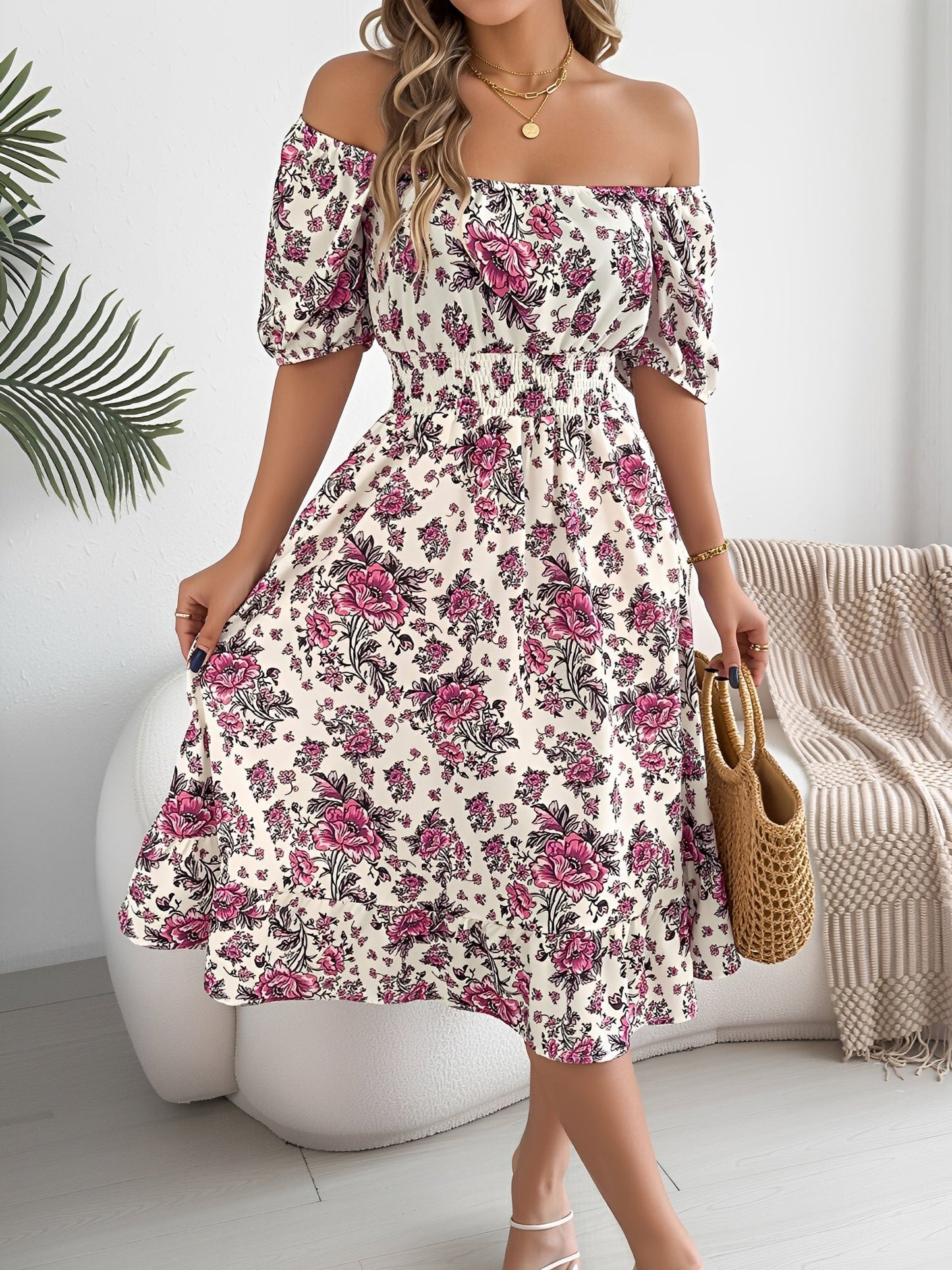 White - Woman wearing a floral print off-the-shoulder midi dress with a smocked waist and short puff sleeves, holding a woven straw bag