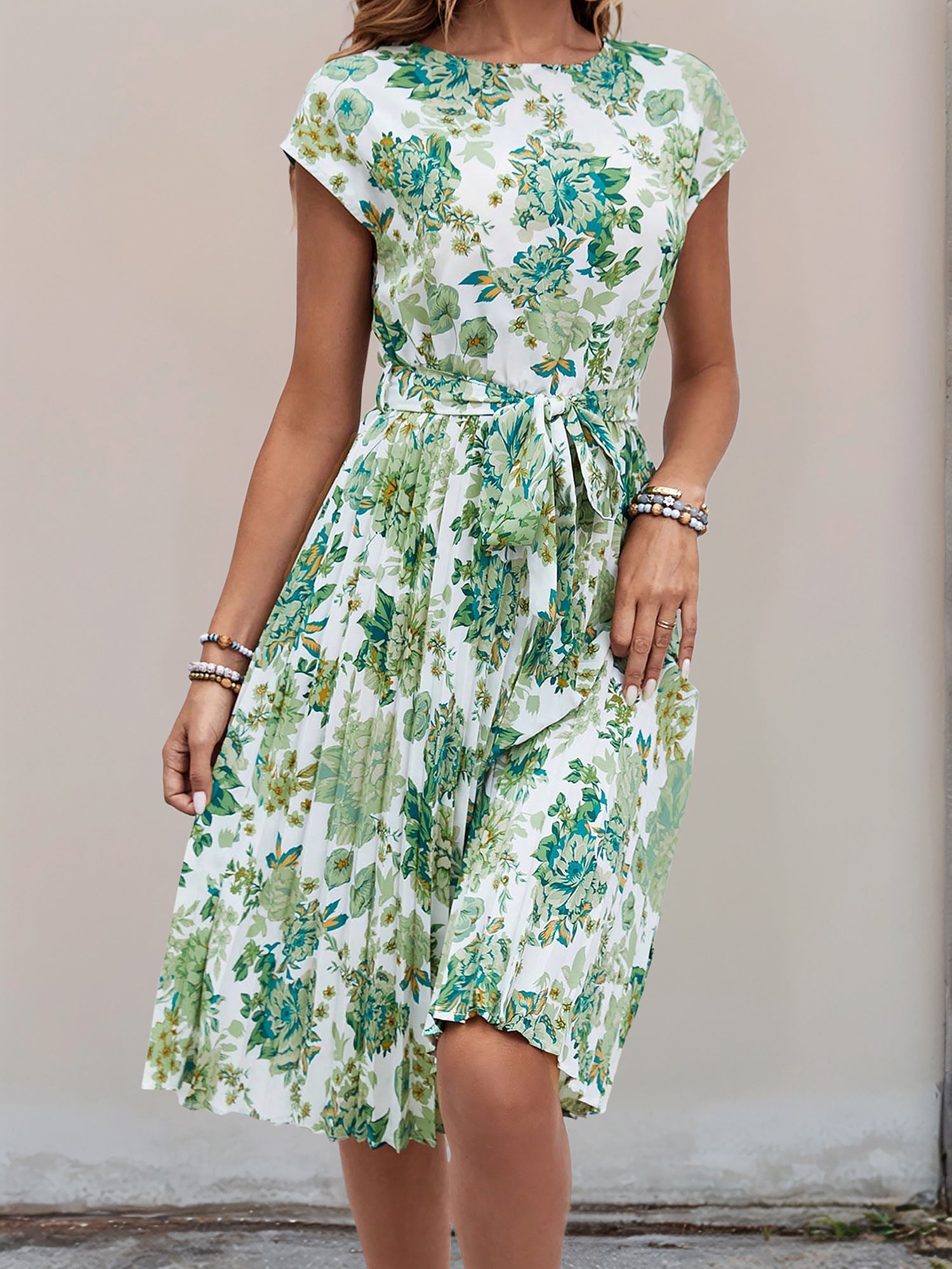 Green - Woman wearing a woven floral cap-sleeve midi dress with a self-tie waist and pleated skirt.