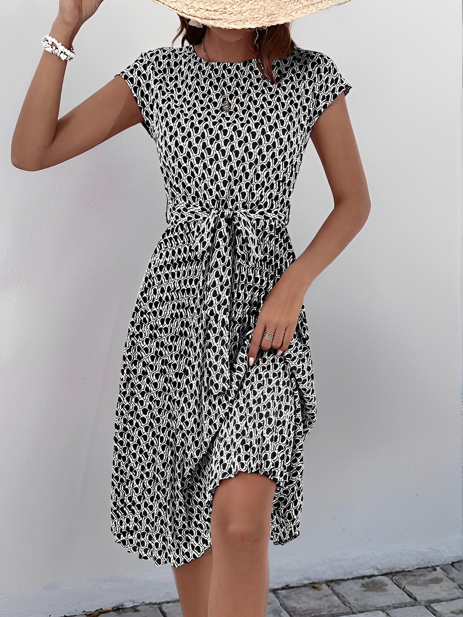 Black - Woman wearing a woven floral cap-sleeve midi dress with a self-tie waist and pleated skirt.