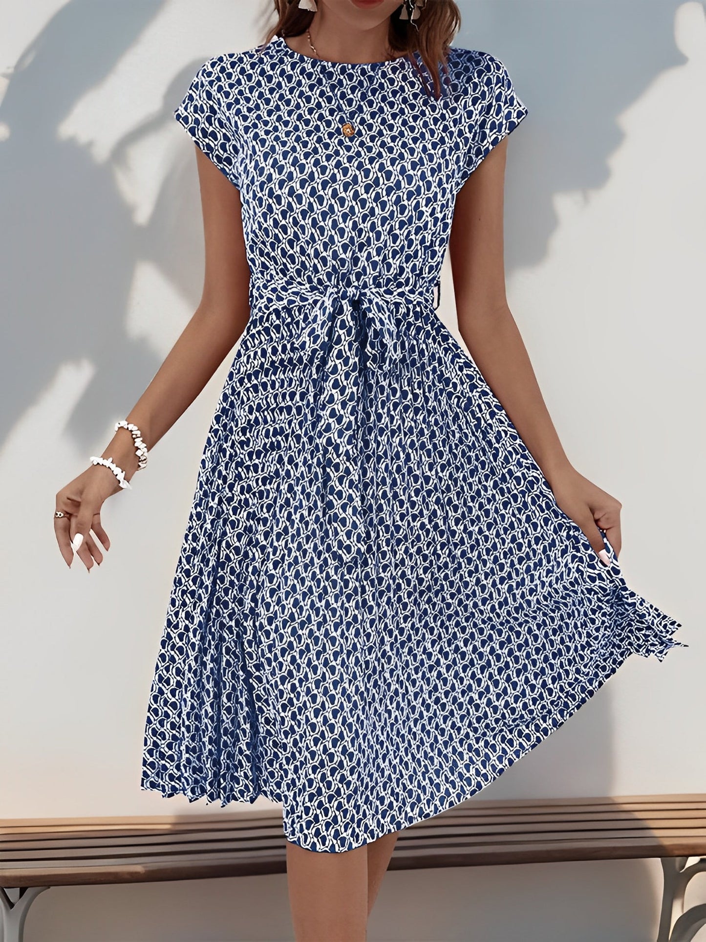 Navy Blue - Woman wearing a woven floral cap-sleeve midi dress with a self-tie waist and pleated skirt.