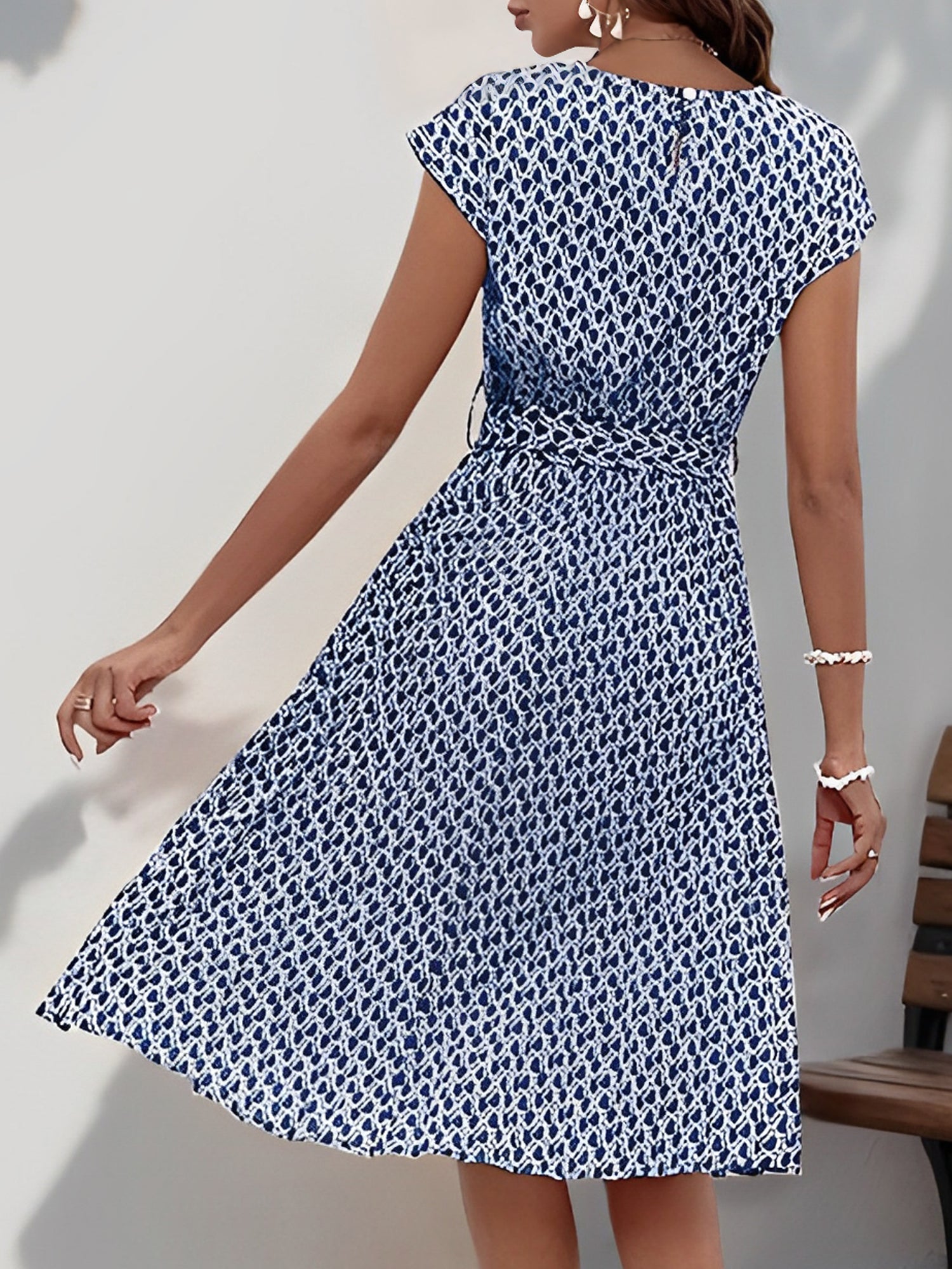 Navy Blue - Woman wearing a woven floral cap-sleeve midi dress with a self-tie waist and pleated skirt.