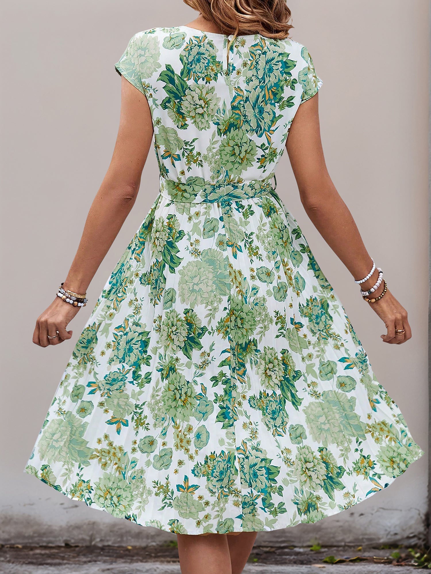 Green - Woman wearing a woven floral cap-sleeve midi dress with a self-tie waist and pleated skirt.