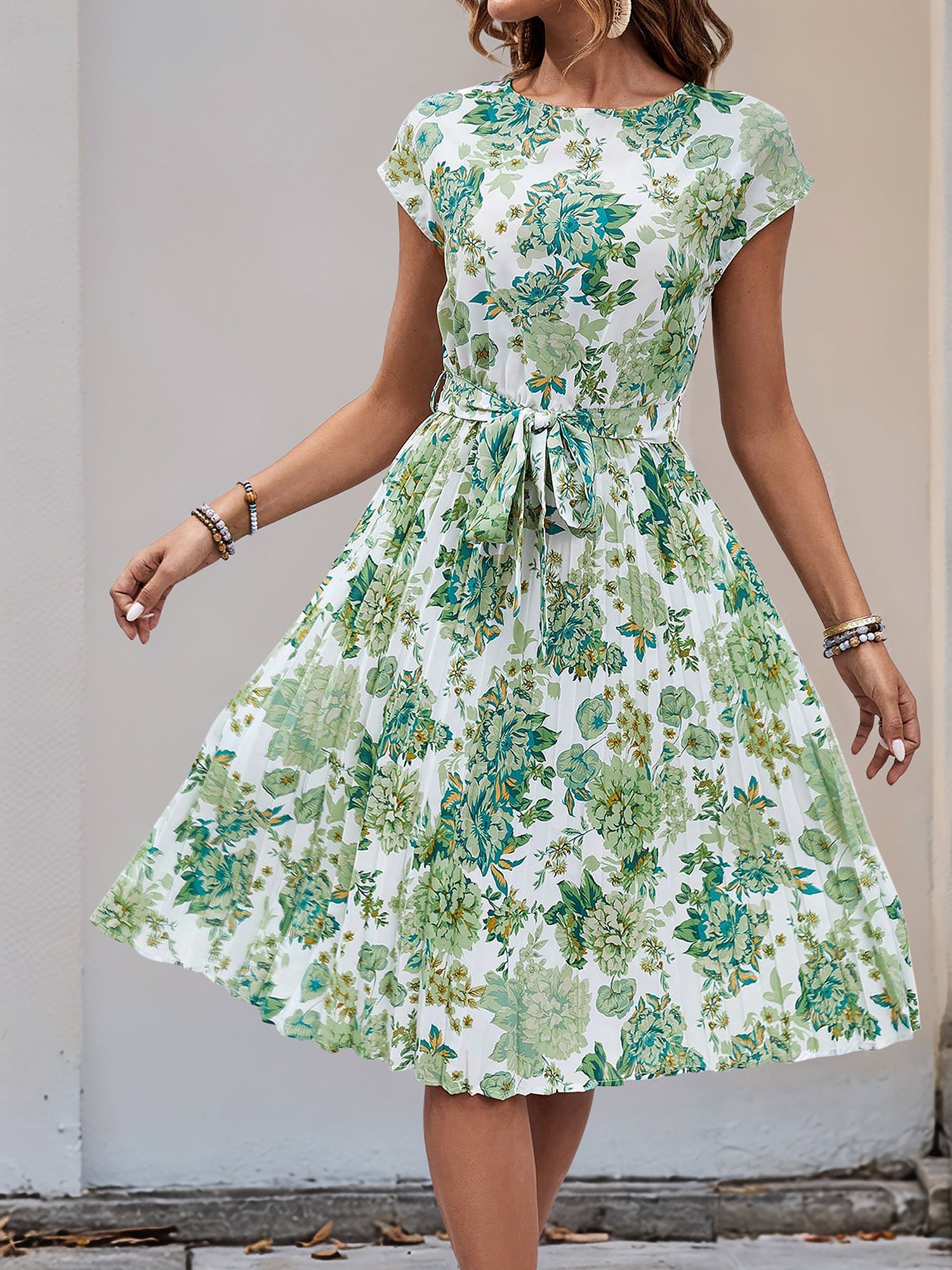 Green - Woman wearing a woven floral cap-sleeve midi dress with a self-tie waist and pleated skirt.